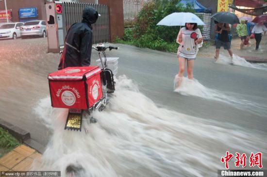 2012年7月21日，北京普降暴雨，朝陽區(qū)北部立水橋南地區(qū)積水嚴重。一小區(qū)門口，積水沿斜坡形成巨大水流，阻礙人們通行。圖片來源：CFP視覺中國